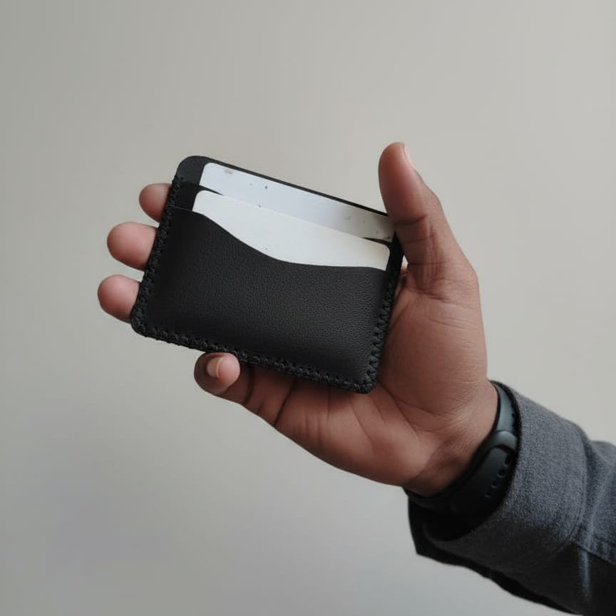 Hand holding a black leather wallet with white interior against a plain background