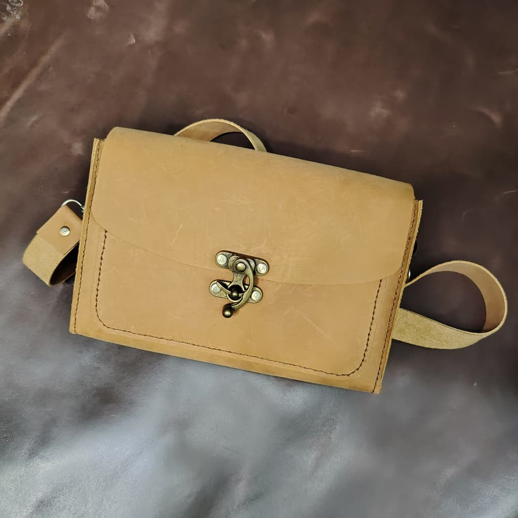 Beige leather bag with a clasp on a brown surface